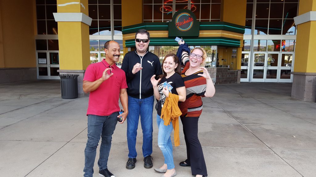 The closed captioning team outside of the movie theater making a C sign with their hands to represent captioning