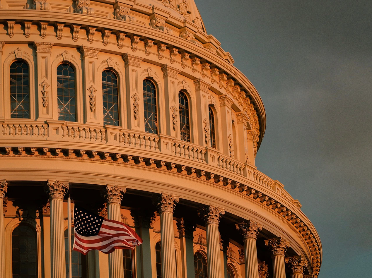 Photo of a capitol building with the US flag waving