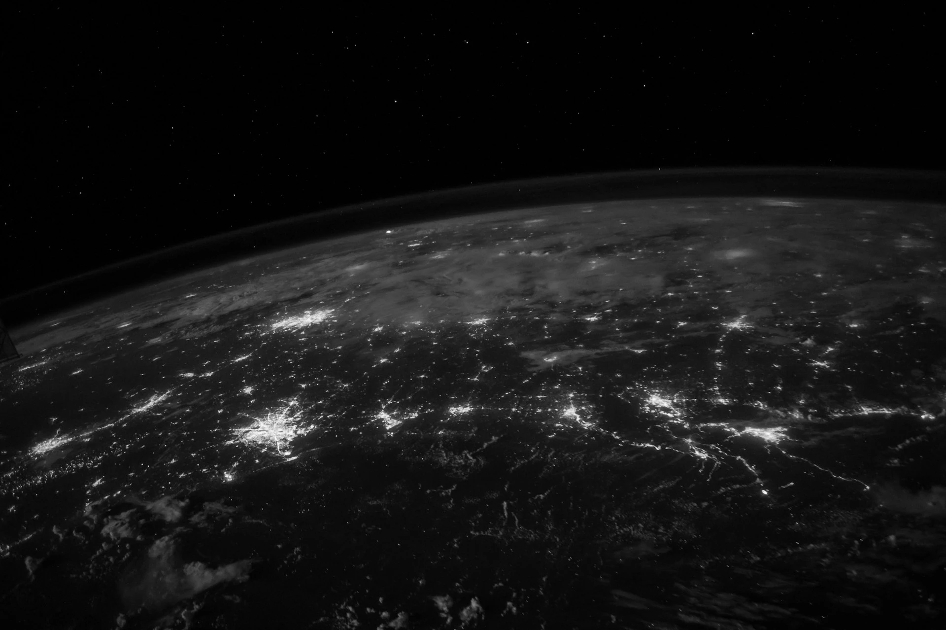 View of Earth from space at night showing illuminated cities and networked regions across the surface.