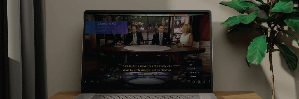 Laptop on a desk displaying the captioned video player with subtitle language options for a panel discussion.