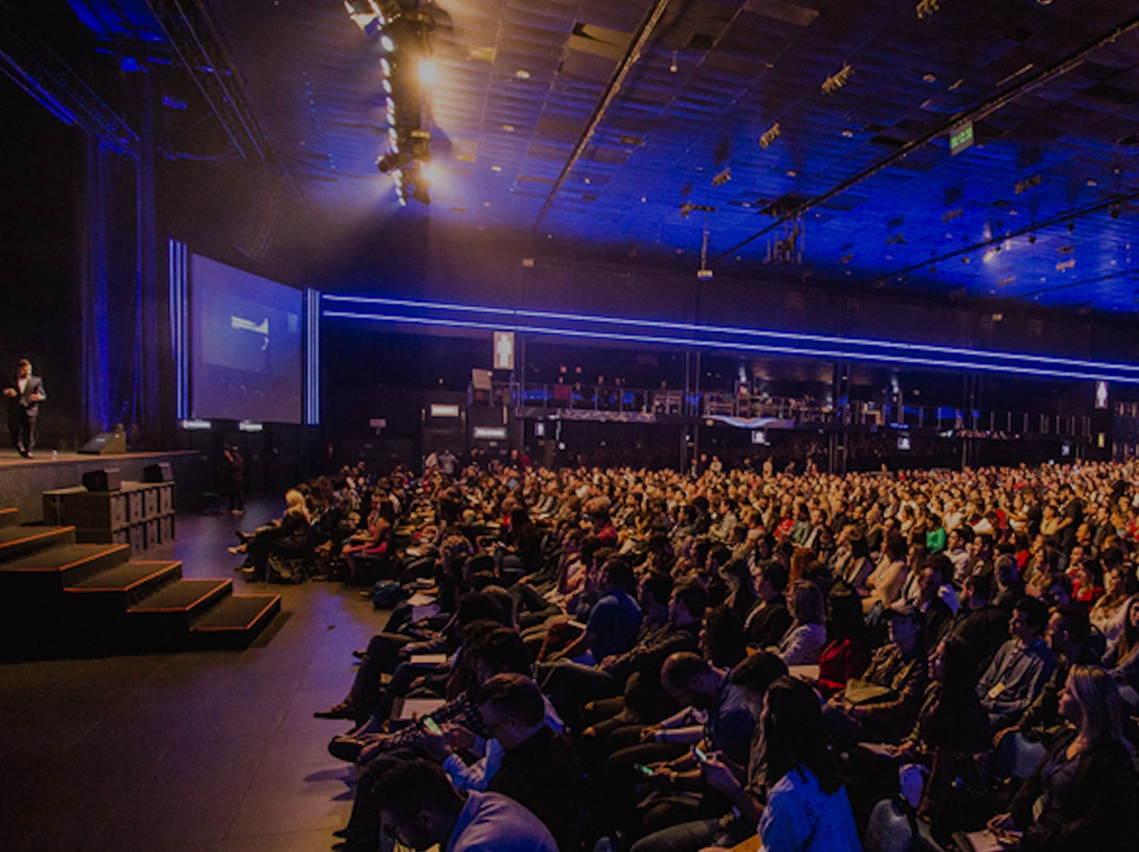 Photo of event with a single speaker on stage talking to a large audience